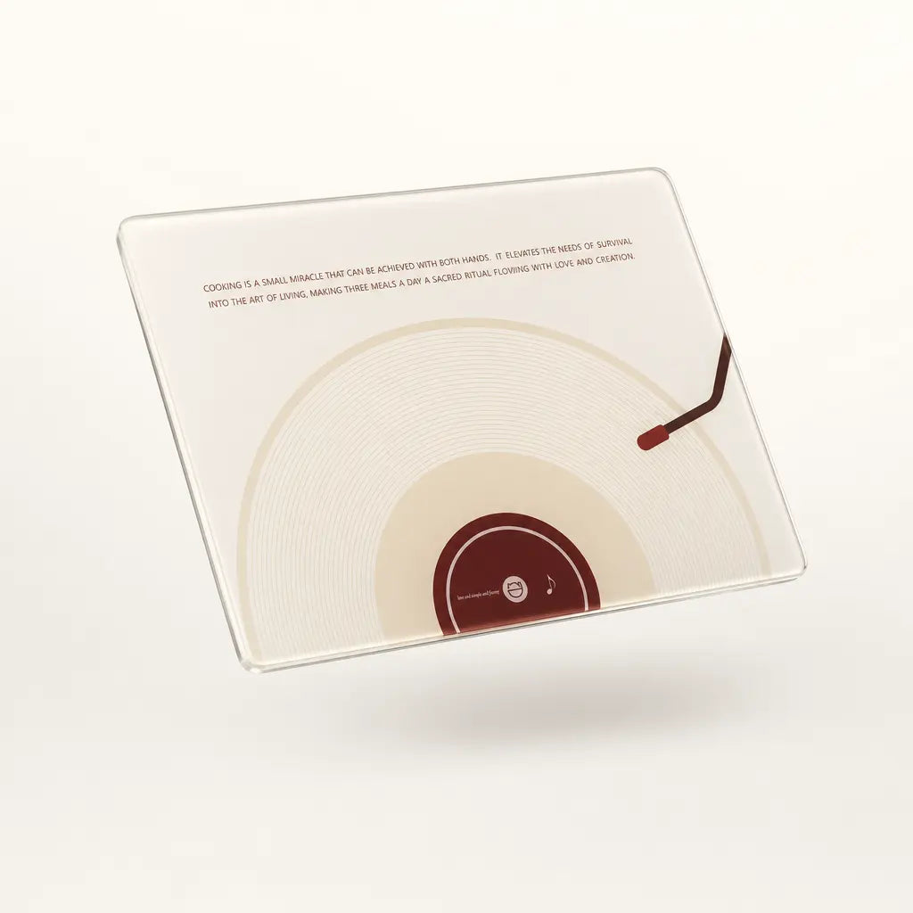 The front view of Alorivo's square tempered glass board, showcasing a high-end minimalist design inspired by album art. A cream and deep burgundy vinyl record silhouette centers the non-porous face, accompanied by delicate serif typography that elevates the daily meal prep into a sensory ritual.