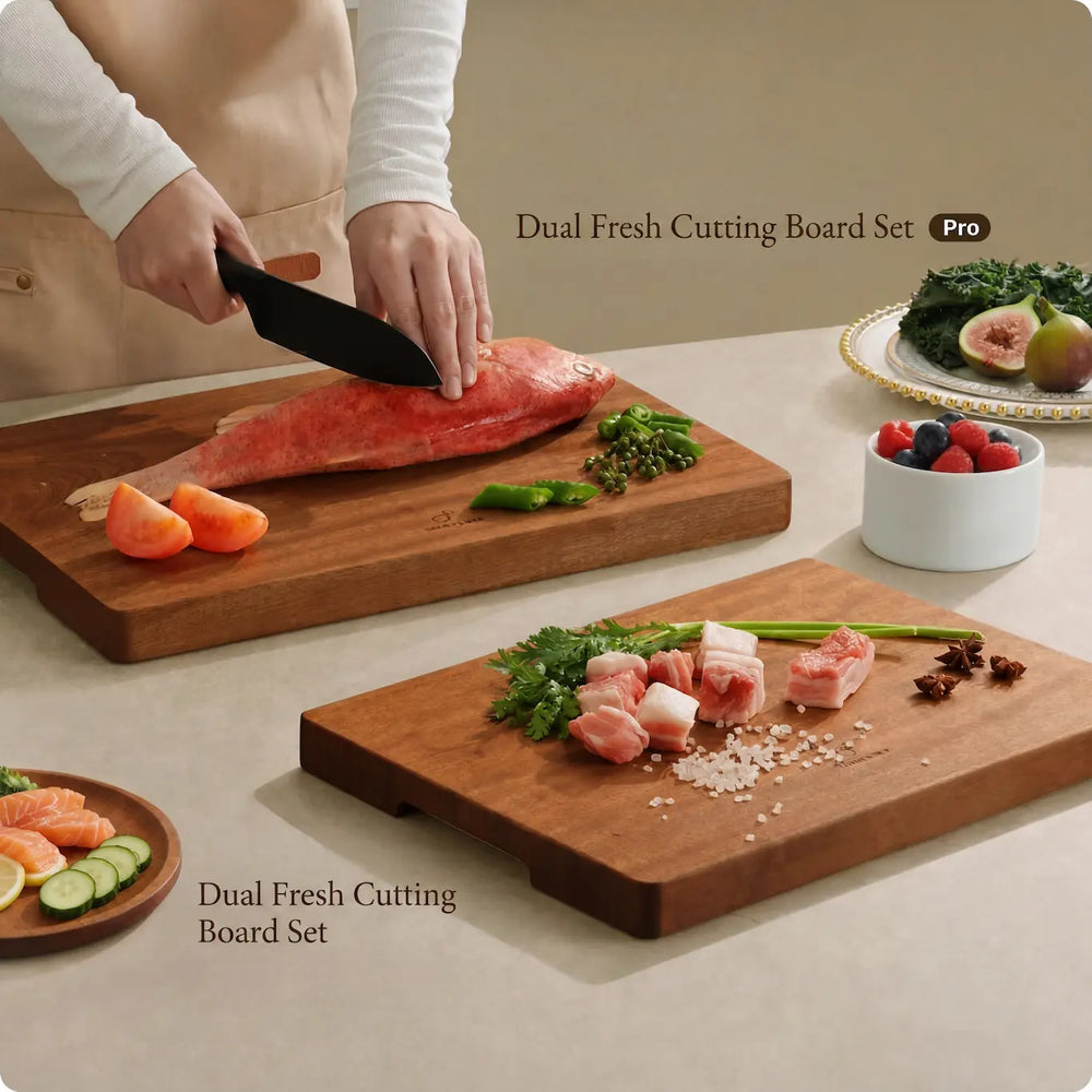 An editorial culinary scene showcasing the Alorivo Dual-Fresh Cutting Board Set and the larger Pro edition on a minimal beige countertop. A chef meticulously prepares a fresh red fish on the rich, textured solid wood board, flanked by vibrant ingredients like sliced tomatoes, green peppers, and a side bowl of fresh berries, evoking a sense of refined, organic living.